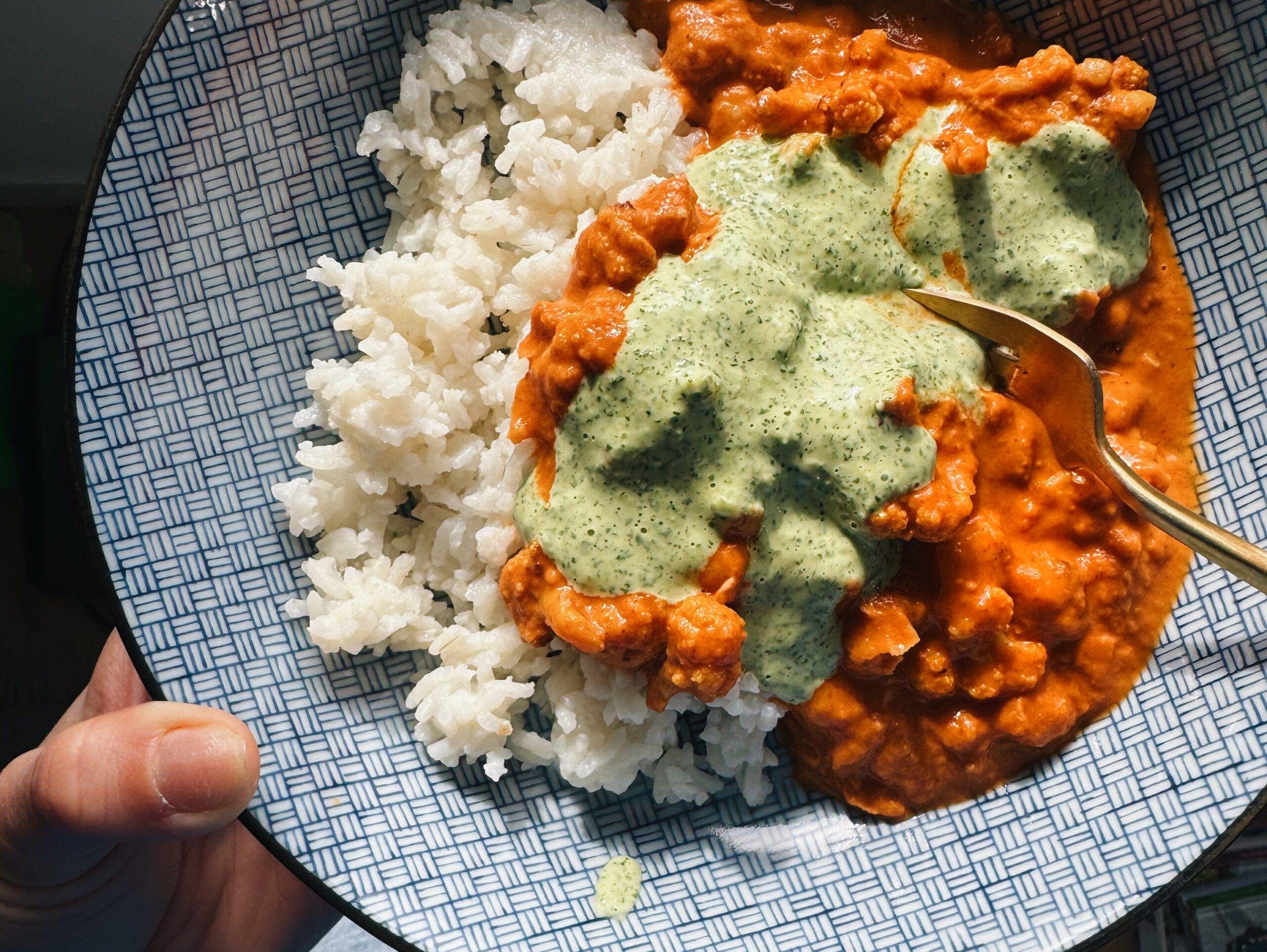 Butter cauliflower in a bowl with rice and mint sauce.