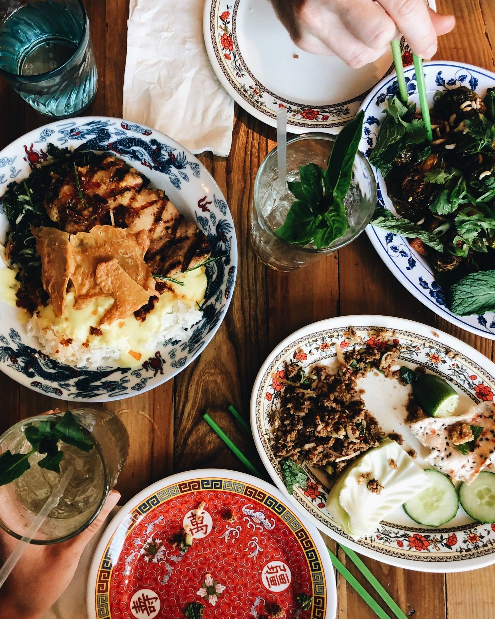 Busy table with plates of food and drinks.