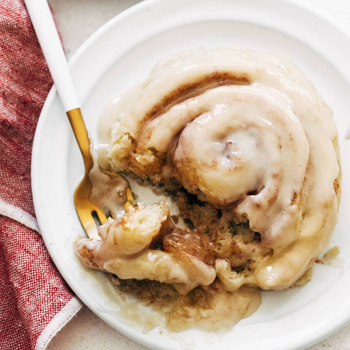 Cinnamon roll on a plate with a fork.