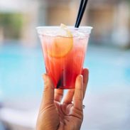 Hand holding a cocktail by the pool.