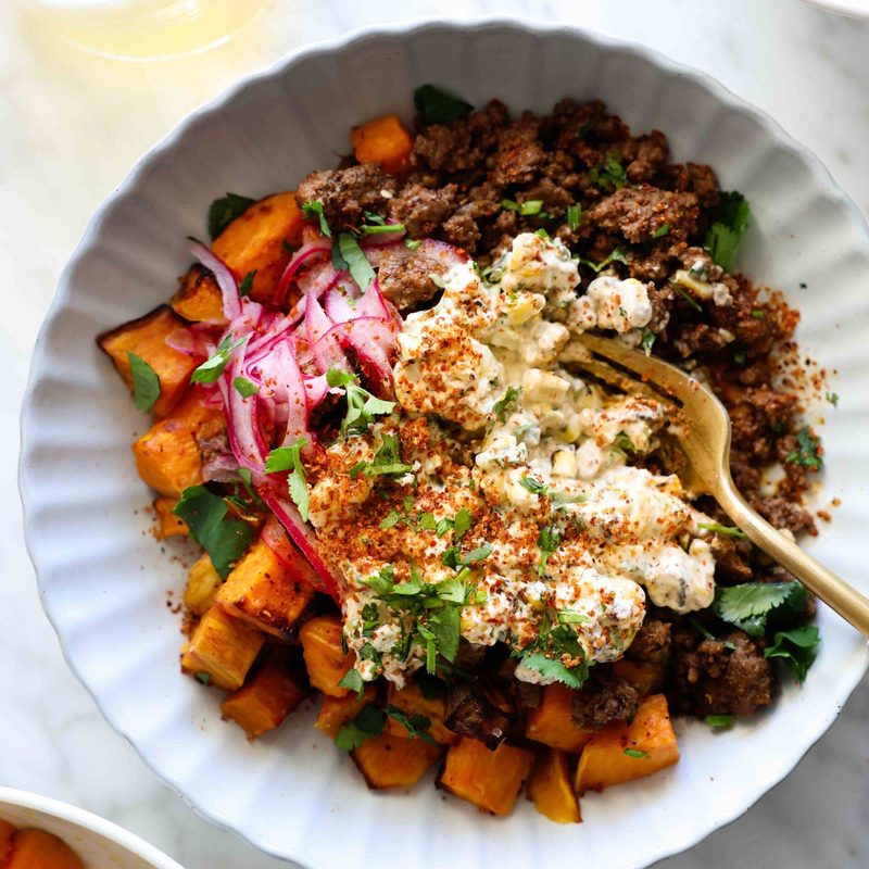 Beef and sweet potato in a bowl with street corn.