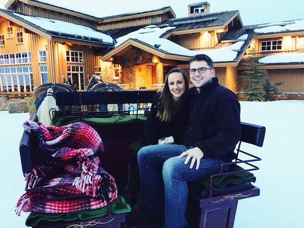 Man and woman in a sled pulled by horses.