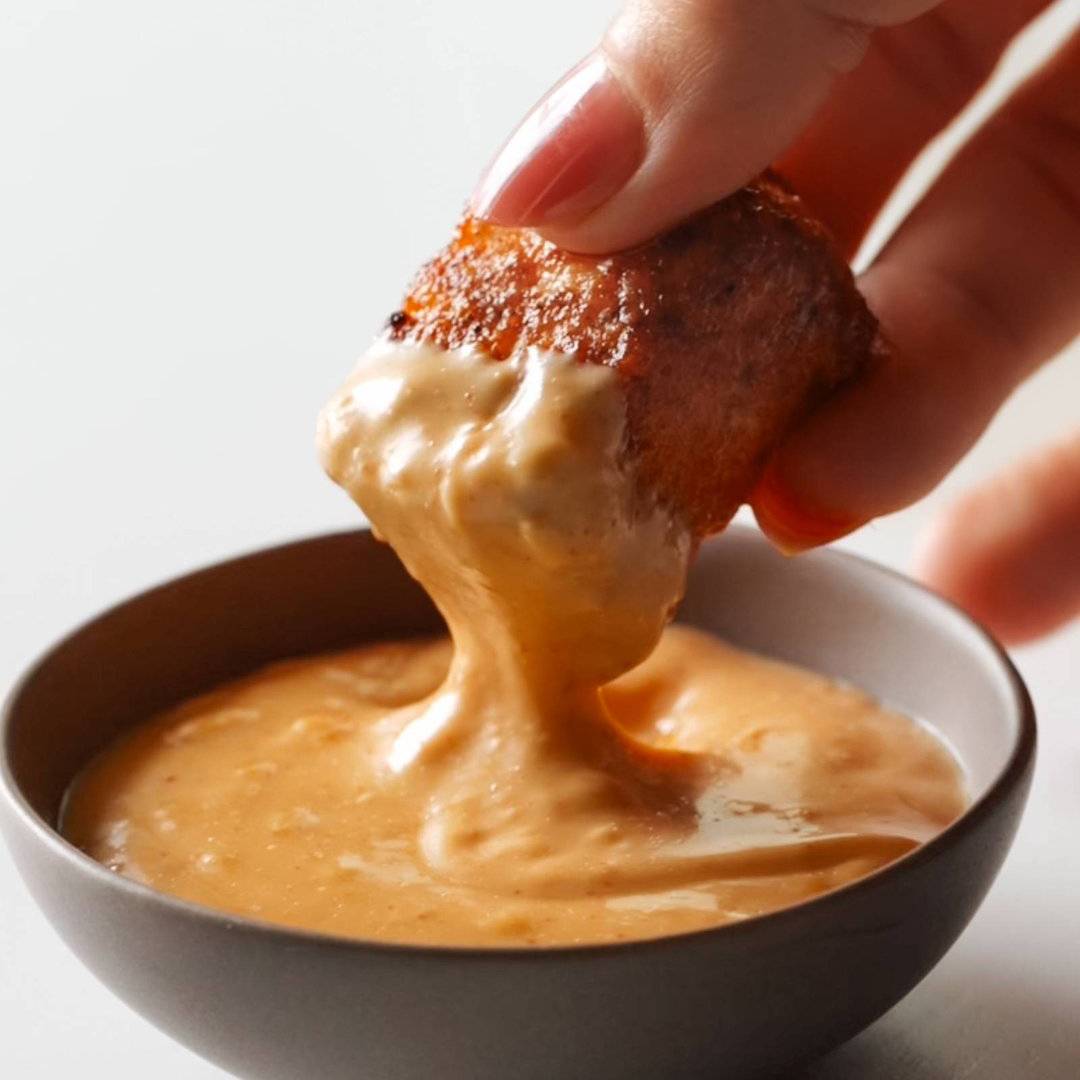 Salmon being dipped into gochujang sauce.