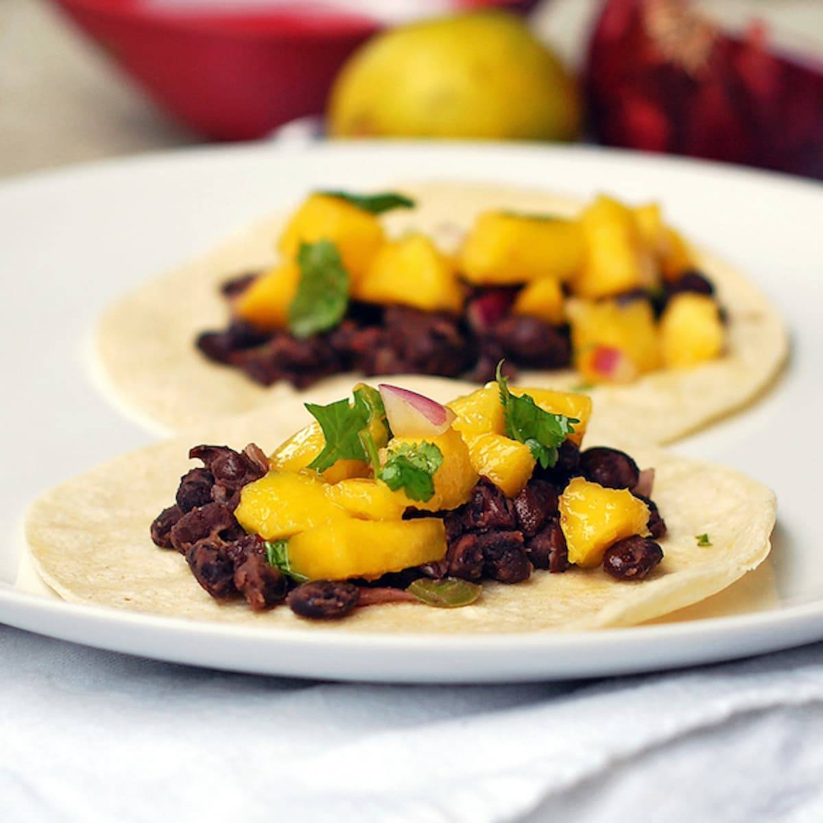 Mango black bean tacos with a creamy coconut sauce drizzled over the top.