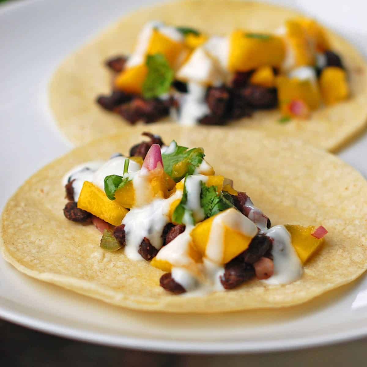 Mango black bean tacos with a creamy coconut sauce drizzled over the top.