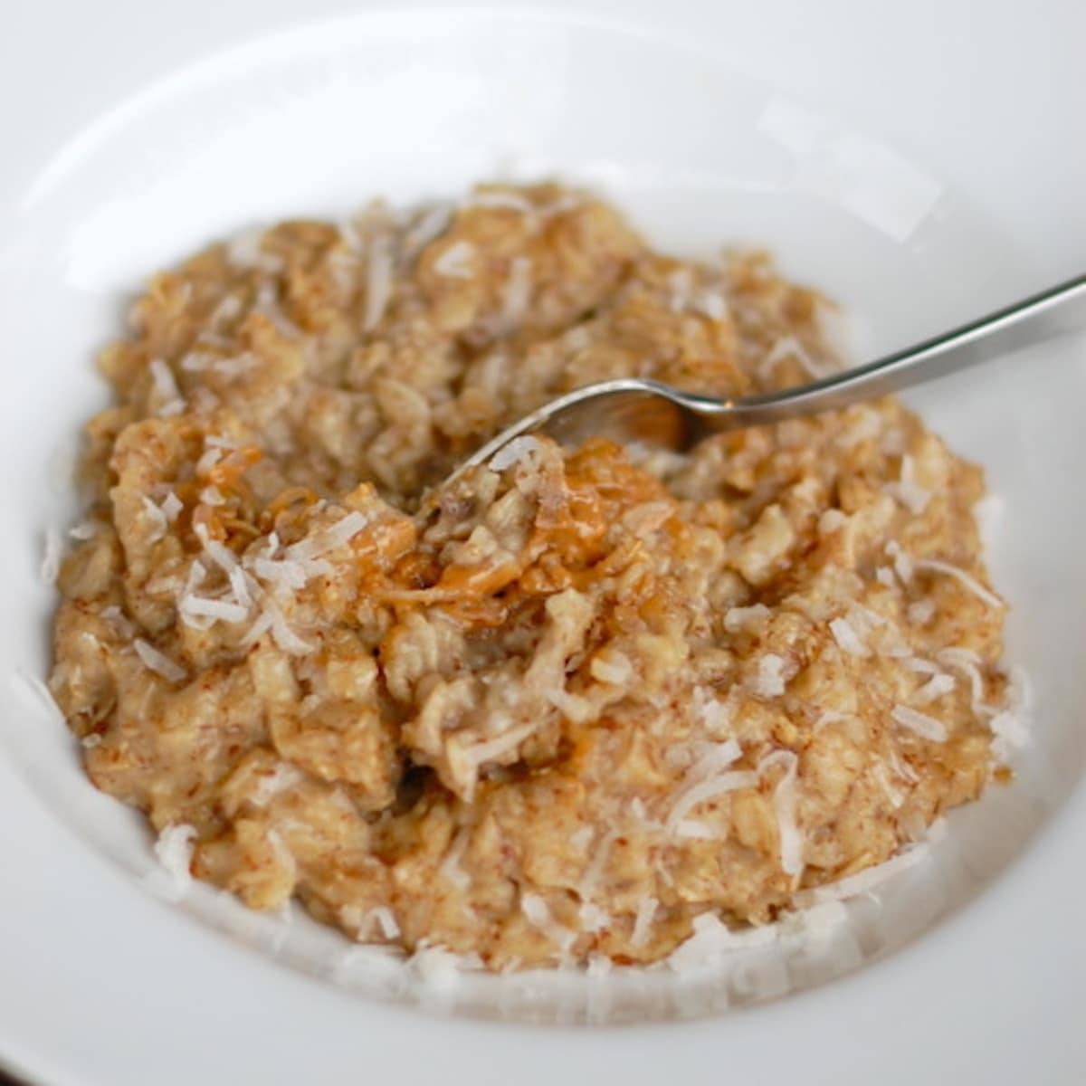Coconut peanut butter oatmeal with coconut shreds and a spoon.