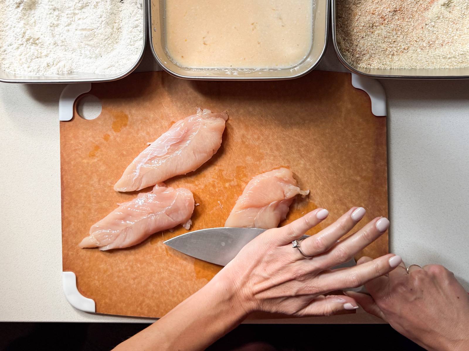 Flattening chicken tenders with a knife.